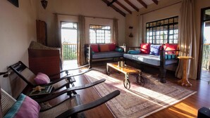 A cozy living room with a wooden ceiling, a sofa with colorful cushions, a wooden coffee table, and a patterned rug. - Saba House & Lodges (Machakos)