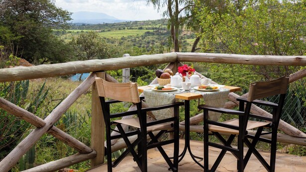 A rustic outdoor dining area with a table set for two, surrounded by wooden chairs, overlooking a scenic landscape. - Saba House & Lodges (Machakos)