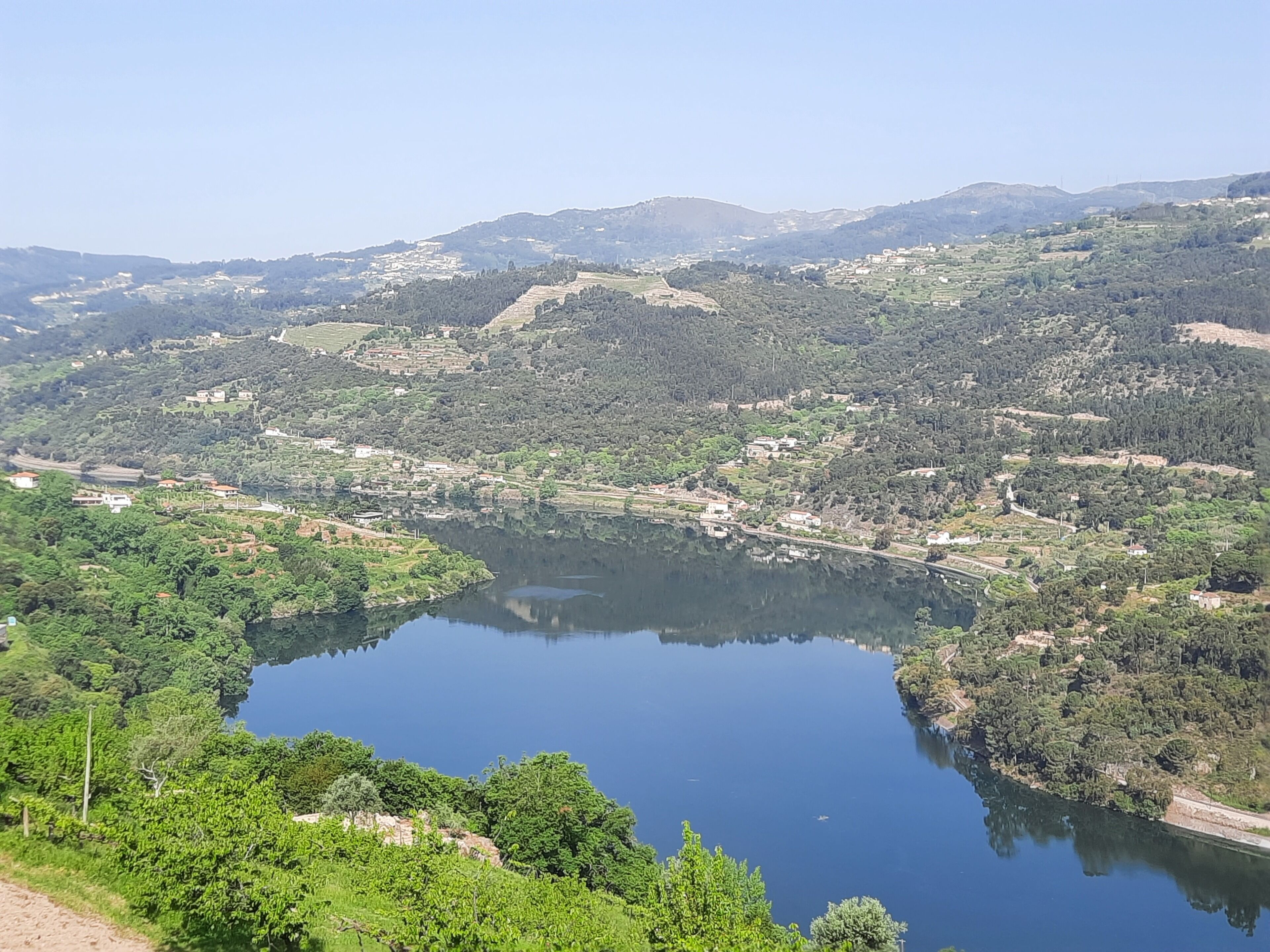 A lake surrounded by hills with scattered buildings and greenery.