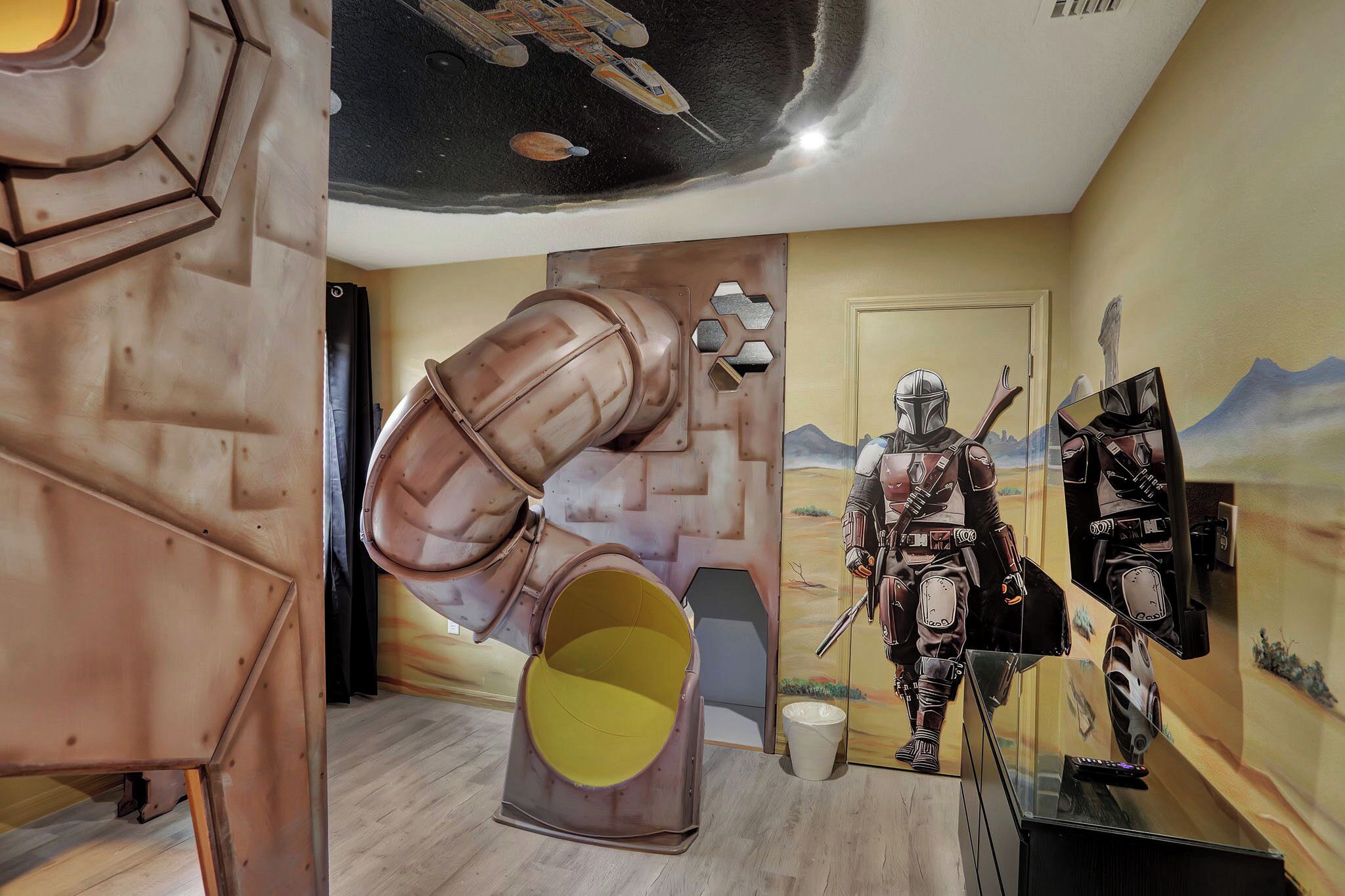 A room with a space-themed mural, a large metallic sculpture, and a Star Wars character figure.