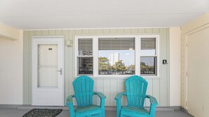 A room with two turquoise chairs, a white door, and a window with blinds. - Sea Winds North 112, North OC, Close to the Beach (Ocean City)