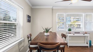 A dining area with a wooden table, chairs, and a ceiling fan. - Sea Winds North 112, North OC, Close to the Beach (Ocean City)