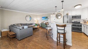 A modern kitchen with white cabinets, a stainless steel refrigerator, and a built-in oven. - Sea Winds North 112, North OC, Close to the Beach (Ocean City)