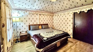 Een slaapkamer met een bed, nachtkastje, lamp en een kledingkast.