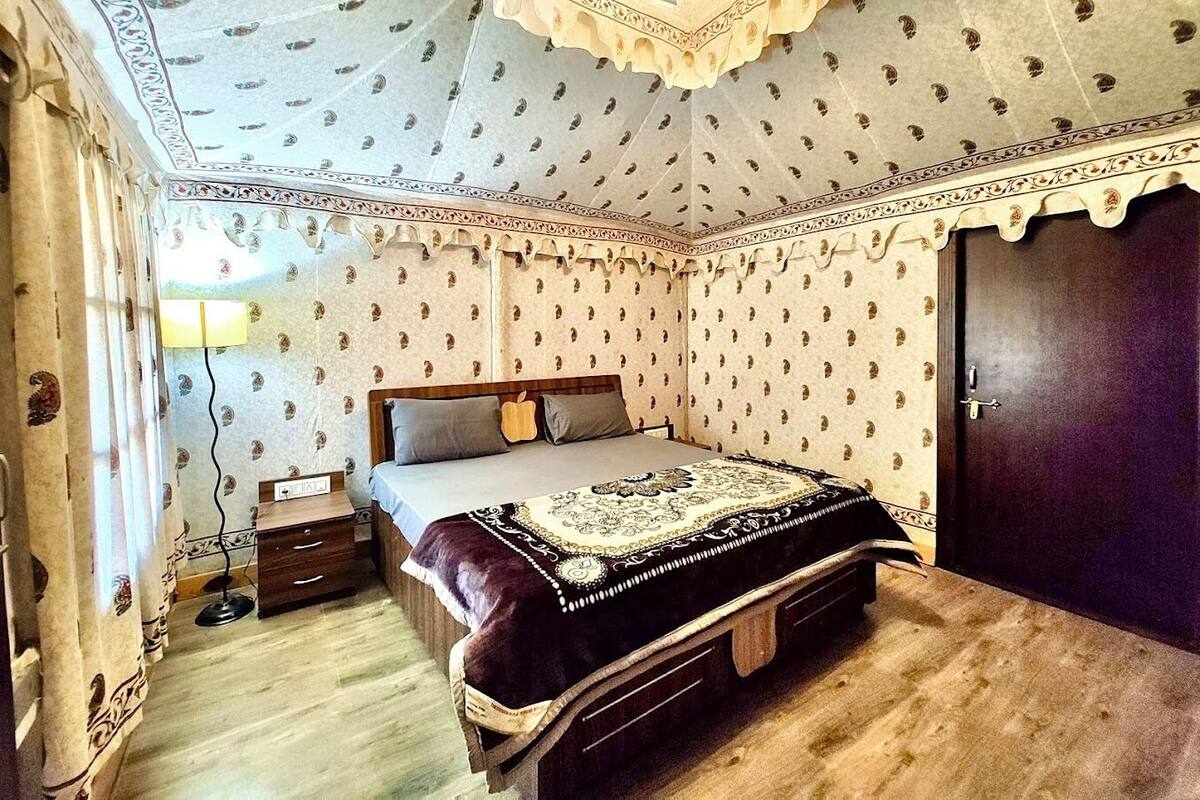 A bedroom with a bed, a nightstand, a lamp, and a wardrobe.