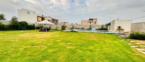 Un amplio espacio exterior con césped cuidado, una piscina y un muro de piedra.