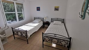 A room with two single beds, a window, a small table, and a wall-mounted lamp. - Villa on the edge of the forest, beach and golf course nearby. Ideal for families! (Moliets-et-Maa)