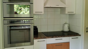A compact kitchen with white cabinets, stainless steel appliances, and a granite countertop. - Villa on the edge of the forest, beach and golf course nearby. Ideal for families! (Moliets-et-Maa)