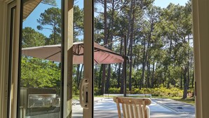 A wooden deck with a wooden chair and a table, overlooking a forested area. - Villa on the edge of the forest, beach and golf course nearby. Ideal for families! (Moliets-et-Maa)