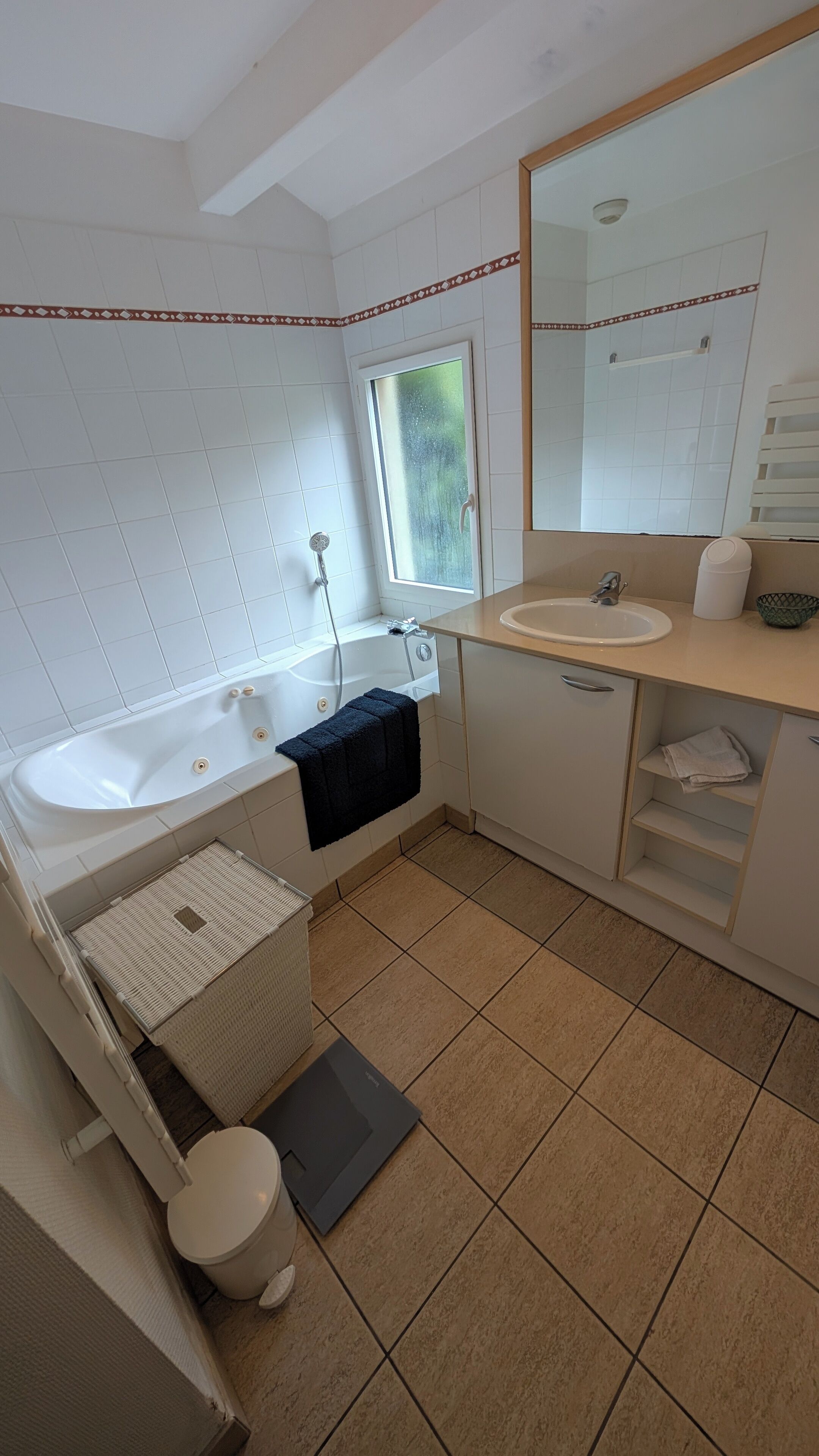 Un baño con bañera, dos lavamanos, un inodoro y un espejo grande.