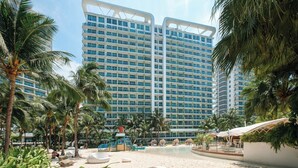 Ein Resort mit Pool, Palmen und einem großen Hotel im Hintergrund.