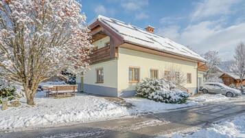 A two-story house with a snow-covered roof and a balcony.