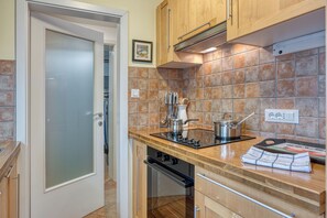 Una cocina con armarios de madera, salpicadero de azulejos, estufa de acero inoxidable y lavavajillas.