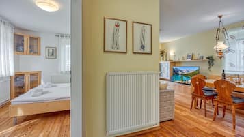 Un salon moderne avec un plancher en bois, un coin repas avec des chaises en bois, un grand téléviseur à écran plat et un radiateur.