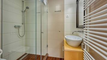 Une salle de bain moderne avec une douche à parois de verre, un lavabo blanc et un meuble-lavabo en bois.
