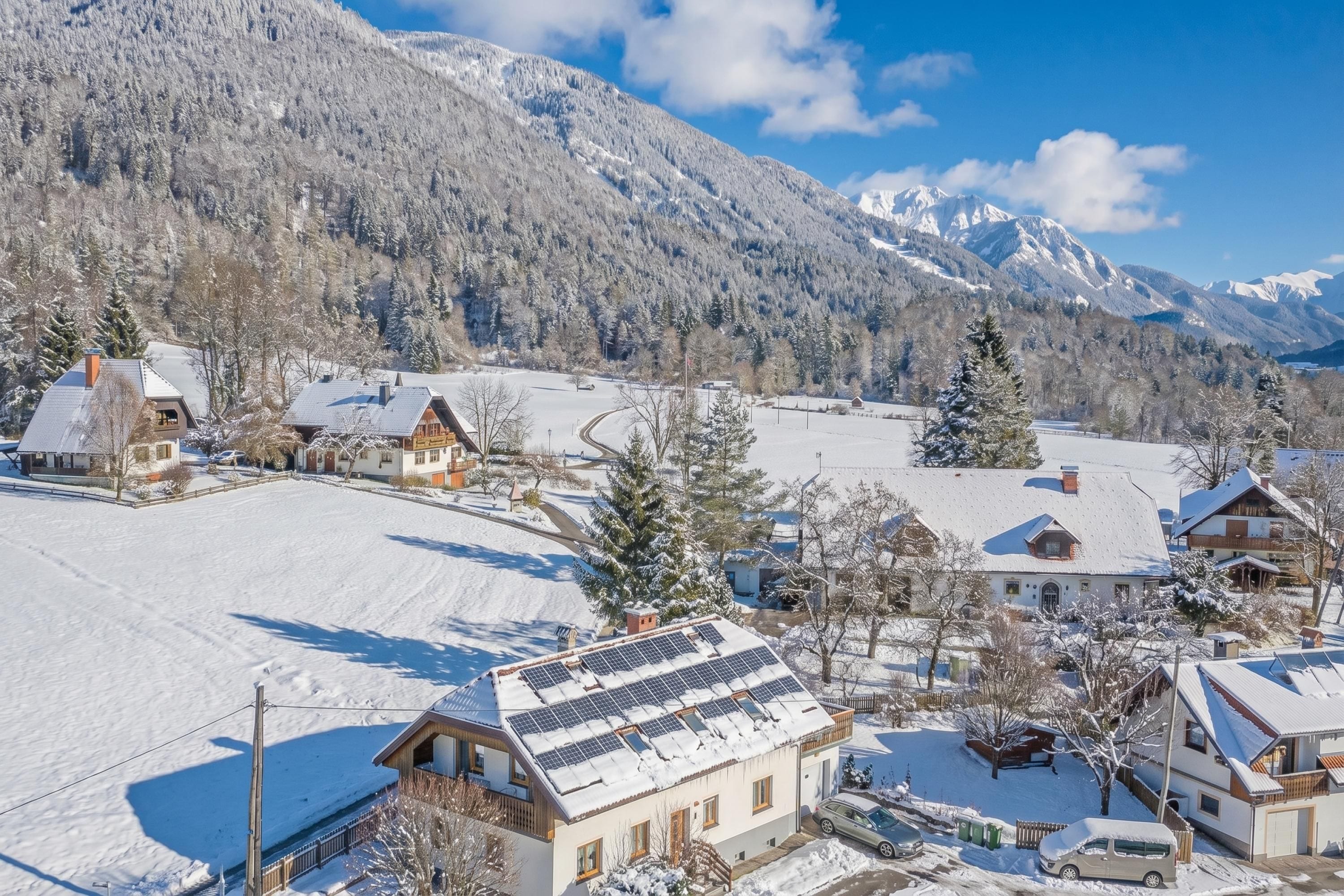 Un village enneigé avec des maisons, une route et des montagnes en arrière-plan.