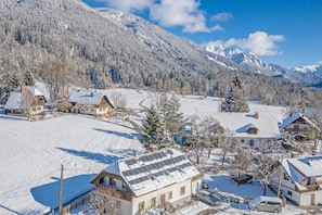 A snow-covered village with houses, a road, and mountains in the background. - Sauna Chalet Planica Near Kranjska Gora (Kranjska Gora)