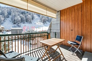 A balcony with a wooden table and chairs, overlooking a snowy mountain landscape. - Theo's House With Terrace (Bardonecchia)