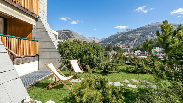 Ein modernes Gebäude mit Balkon, zwei Liegestühlen und Bergblick.