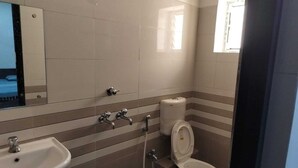 Un baño con lavamanos, inodoro y espejo.