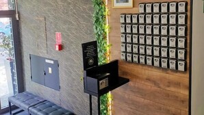 A reception area with a stone wall, a green vertical garden, a clock, a framed picture, and a row of room keys. - Great Polonia Kraków City Center (Kraków)
