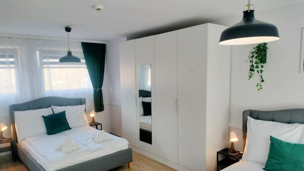 A modern bedroom with two beds, a large wardrobe, and a hanging plant. - Great Polonia Kraków City Center (Kraków)