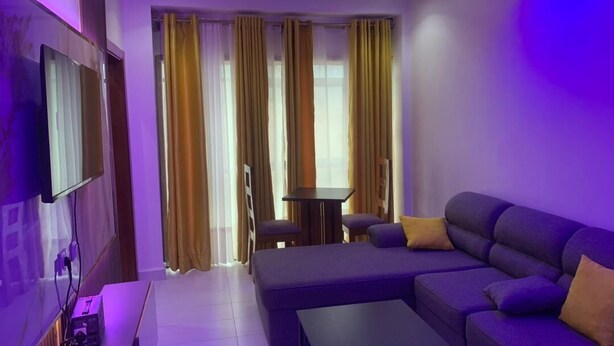 Uma sala de estar moderna com sofá seccional, televisão de tela plana na parede e uma mesinha.