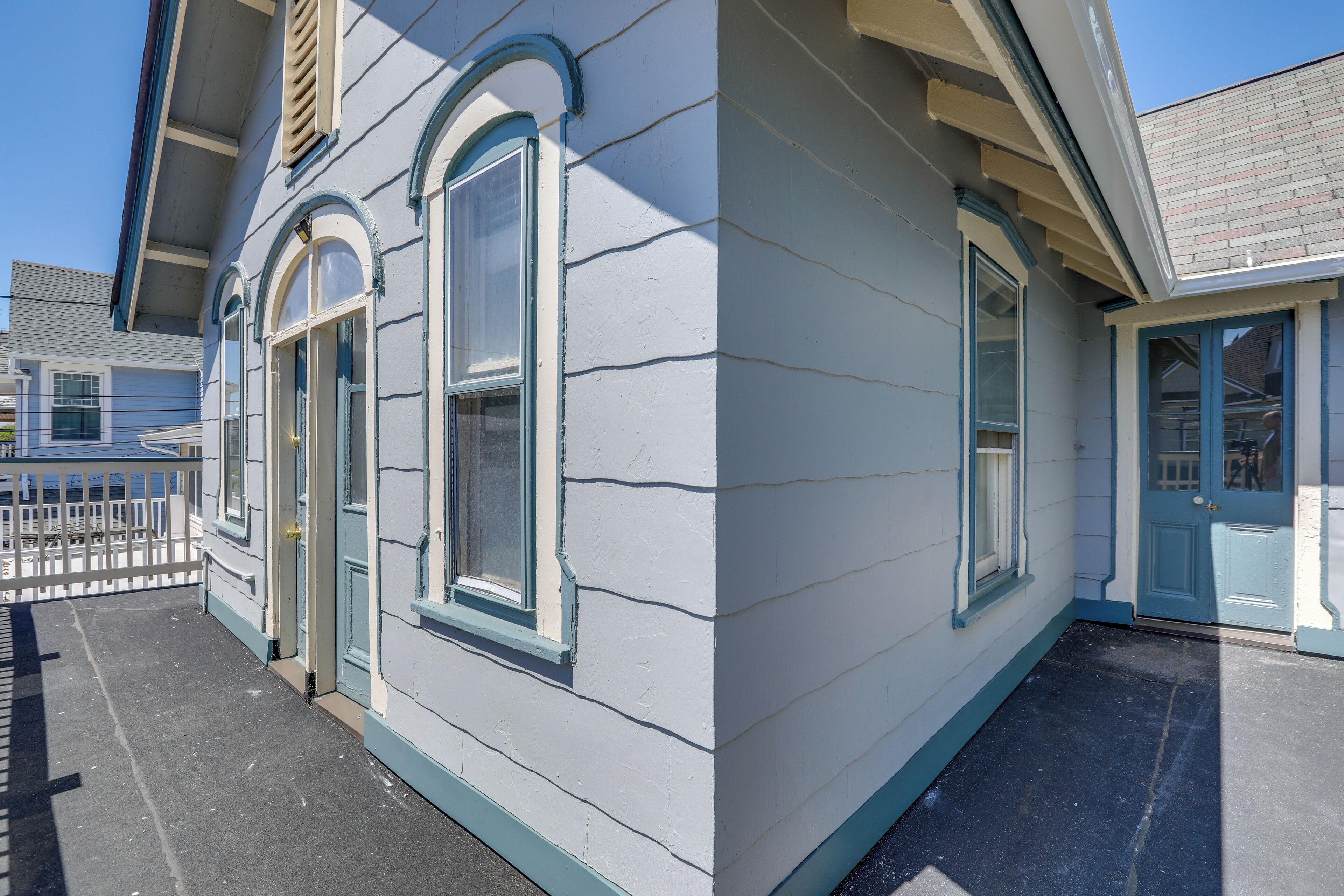 A corner of a building with a white exterior, a blue door, and a small porch area.