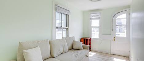 A living room with a beige sofa, a wooden side table, and a white door.