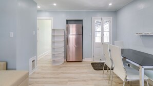 Una cocina moderna con un refrigerador de acero inoxidable, sillas blancas y una mesa de comedor negra.