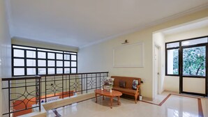 Amplia sala de estar con sofá, mesa de centro, ventanas grandes y un balcón con barandilla.