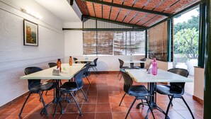 Un comedor con mesas y sillas, un techo con diseño decorativo, y una ventana con persianas.