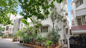 Zona residencial con edificios blancos, plantas en macetas y un portón negro.