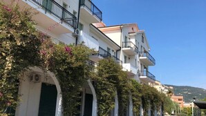 A multi-story building with balconies, arched doorways, and a clear sky. - Blu Apartments (Pietra Ligure)