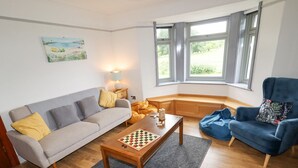 A living room with a sofa, armchair, and a coffee table with a chessboard. - Segrwyd Uchaf (Denbigh)