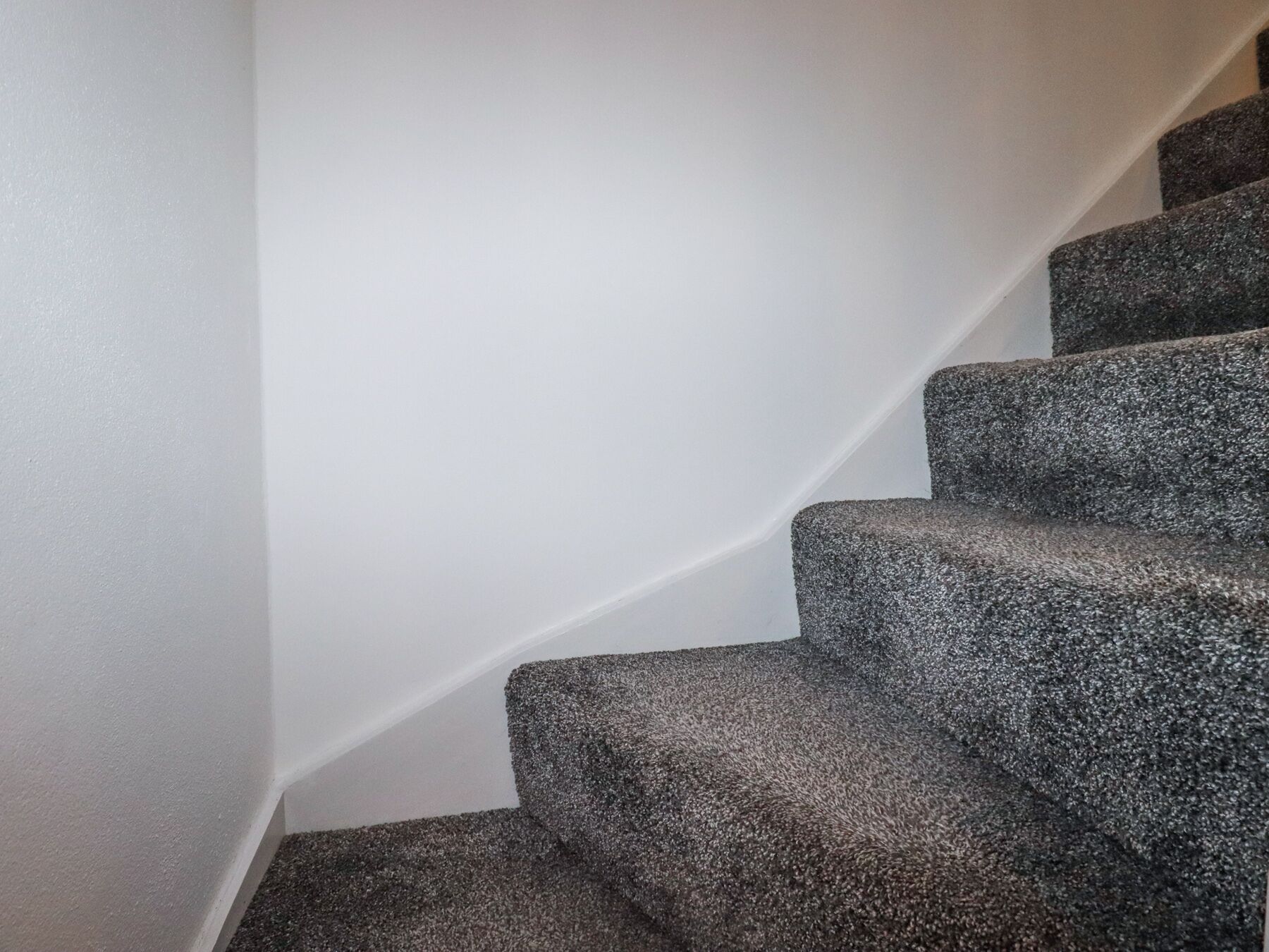 Eine Treppe mit dunklem Teppich und weißen Wänden.