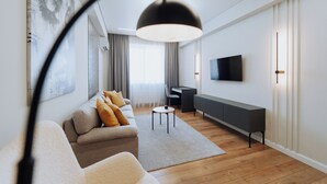 A modern living room with a sofa, a coffee table, a TV mounted on the wall, and a desk with a chair.
