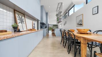 Une cuisine moderne avec un grand îlot central, des chaises noires et une table à manger en bois.