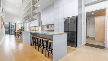 A modern kitchen with a central island, bar stools, and a stainless steel refrigerator.