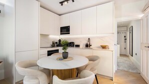 Una cocina moderna con armarios blancos, una mesa redonda de comedor y dos sillas.