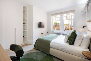 Een slaapkamer met een bed, een televisie, een raam met uitzicht en een kledingkast.