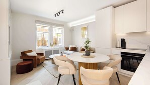 Una cocina moderna con armarios blancos, una mesa redonda con sillas y una planta en maceta sobre la mesa.