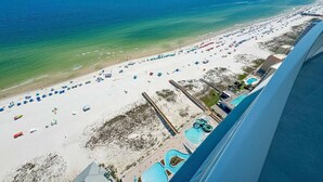 An aerial view of a beach with numerous umbrellas and a swimming pool area.