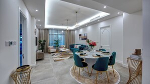 A modern dining area with a round table, chairs, and a chandelier. - Durrani Homes - Arabian luxury at Souk Al Bahar besides Burj Khalifa & Dubai Mall (Dubai)