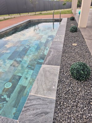 A swimming pool with a tiled edge and a pebble-lined walkway. - Spacious modern villa with swimming pool (Saint-Sernin)