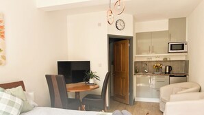 Een kleine hotelkamer met een bed, een eettafel met stoelen, een kitchenette en een televisie.