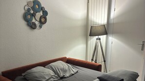 Une chambre à coucher avec un lit, un canapé rouge, une lampe et un élément de décoration murale.