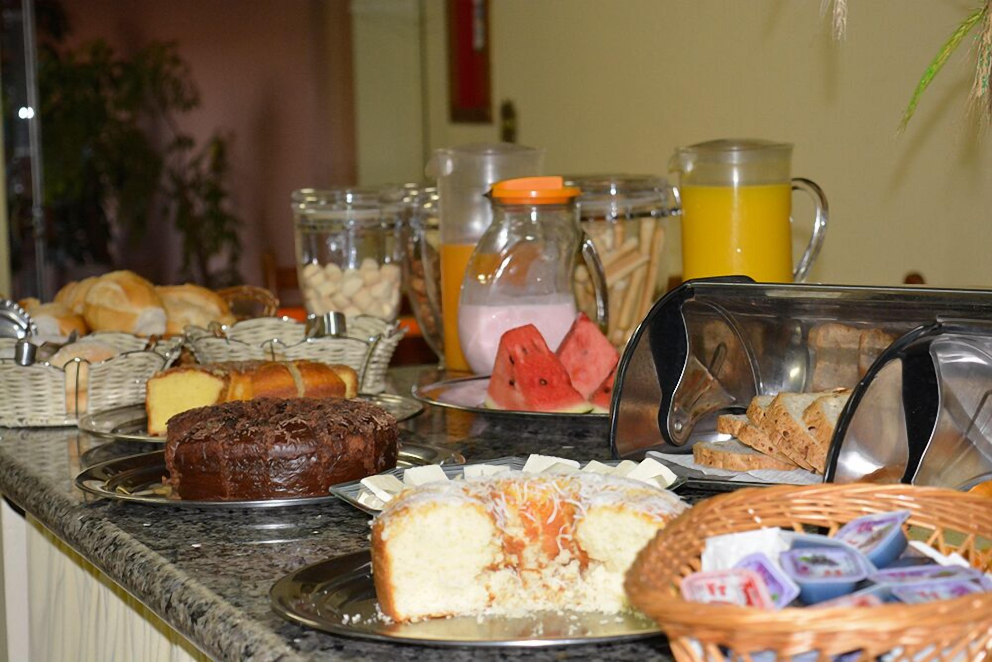 A buffet with various food items including cakes, pastries, and a watermelon.