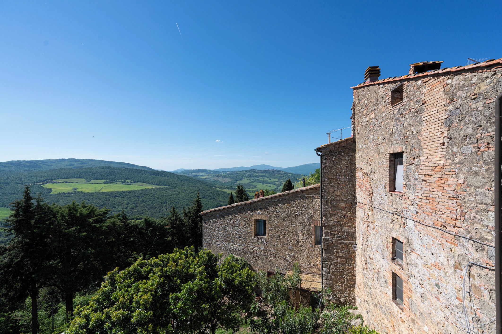 A stone building with a view of green hills and a clear sky.