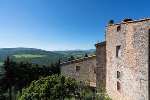 Un edificio de piedra con vistas a colinas verdes y un cielo despejado.